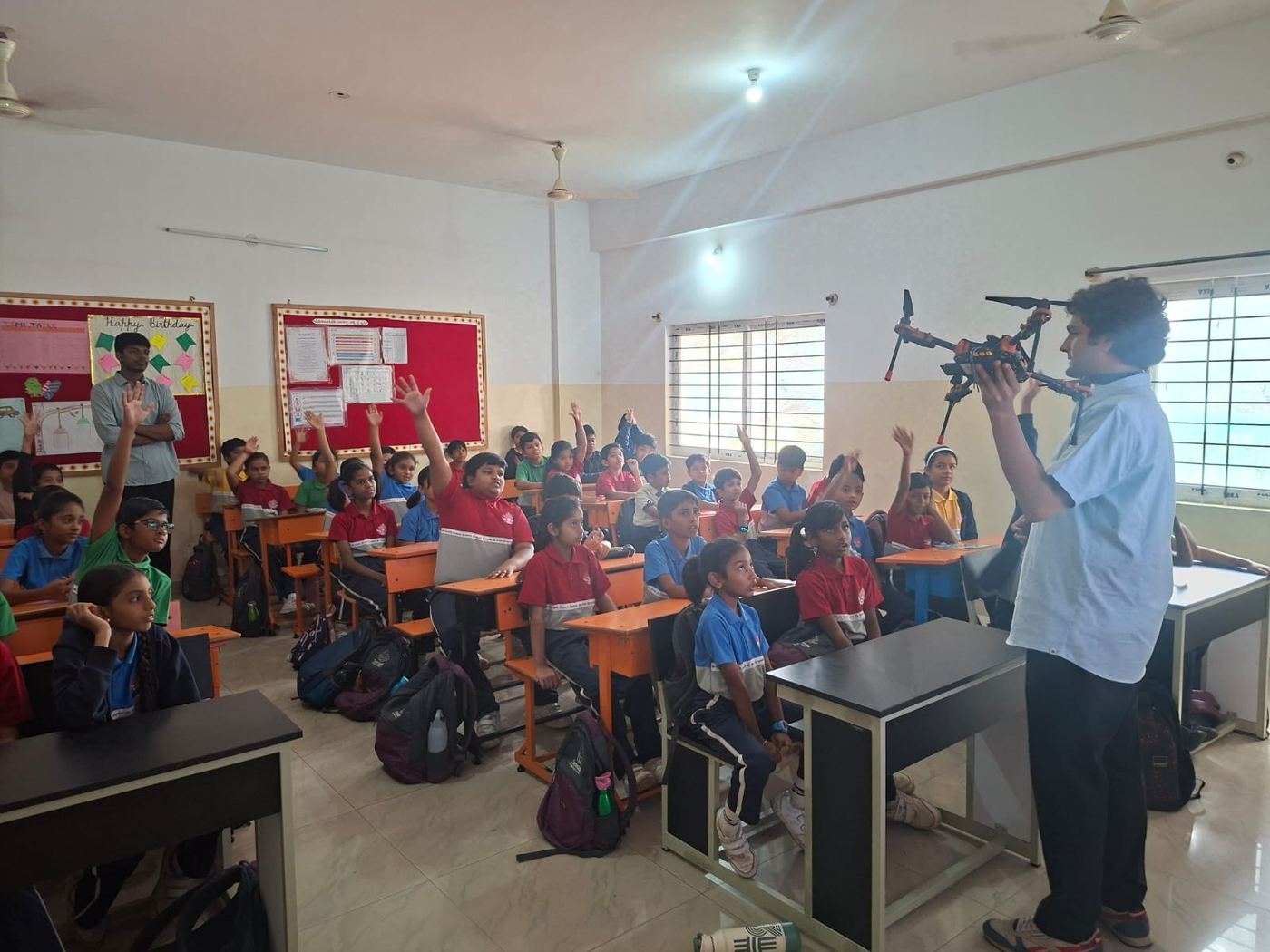 Students raise their hands during a drone demo in class