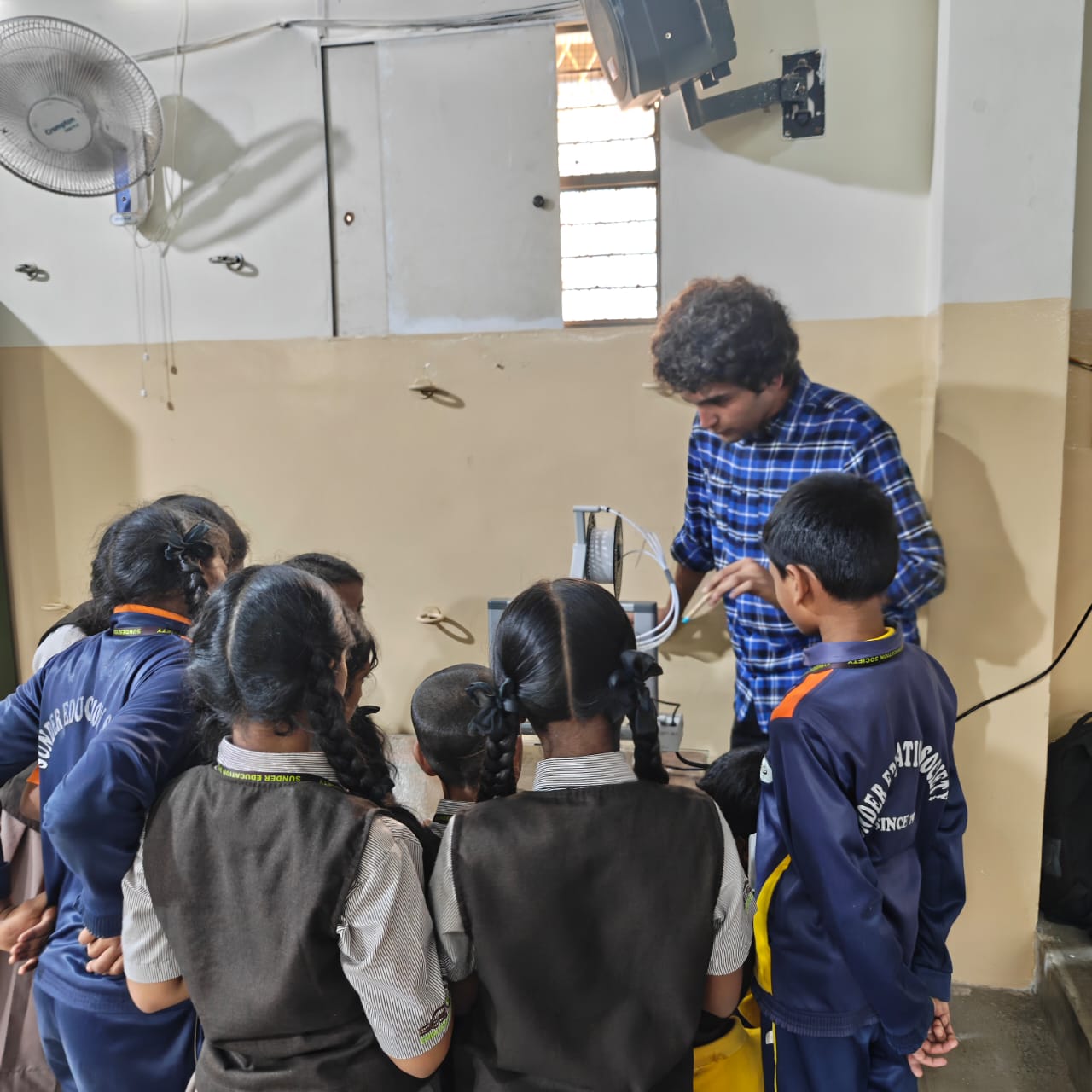 Students gathered around a mentor demonstrating equipment in class